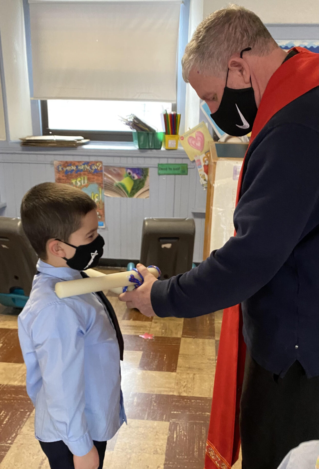 Fr. Frank blesses a child's throat with crossed candles on St. Blaise Day